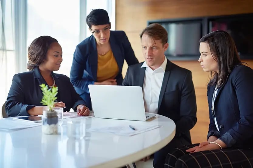 Professionals gathered around a laptop.