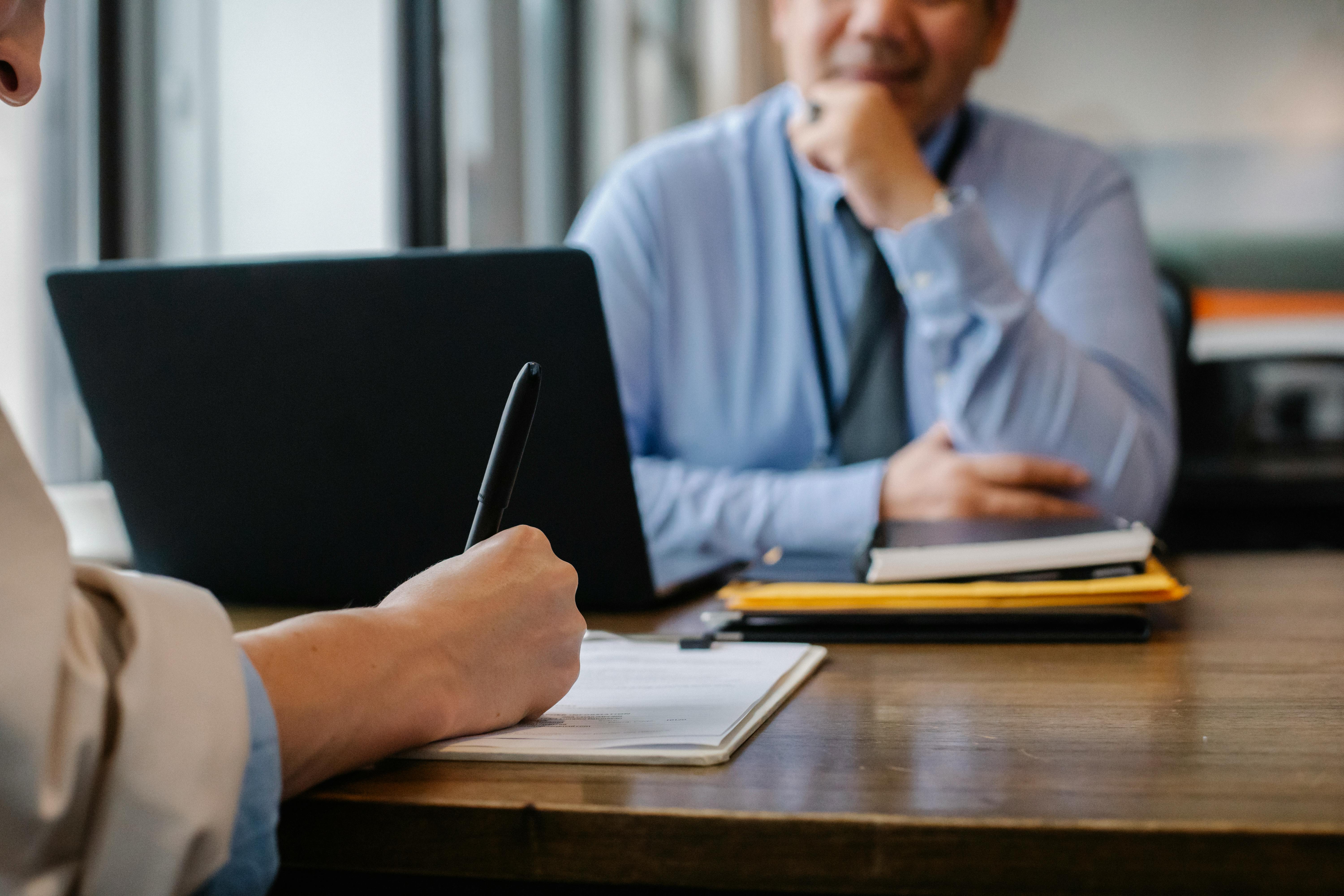 People meeting at a desk, one taking notes