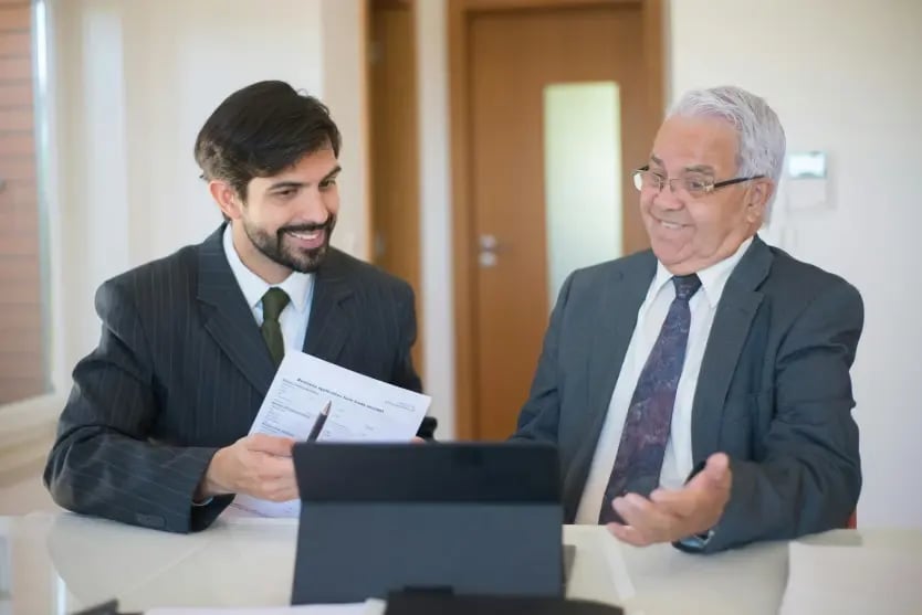 Two people reviewing documents on a laptop