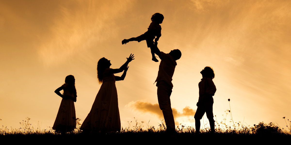 Family enjoying each other's company outdoors at sunset.