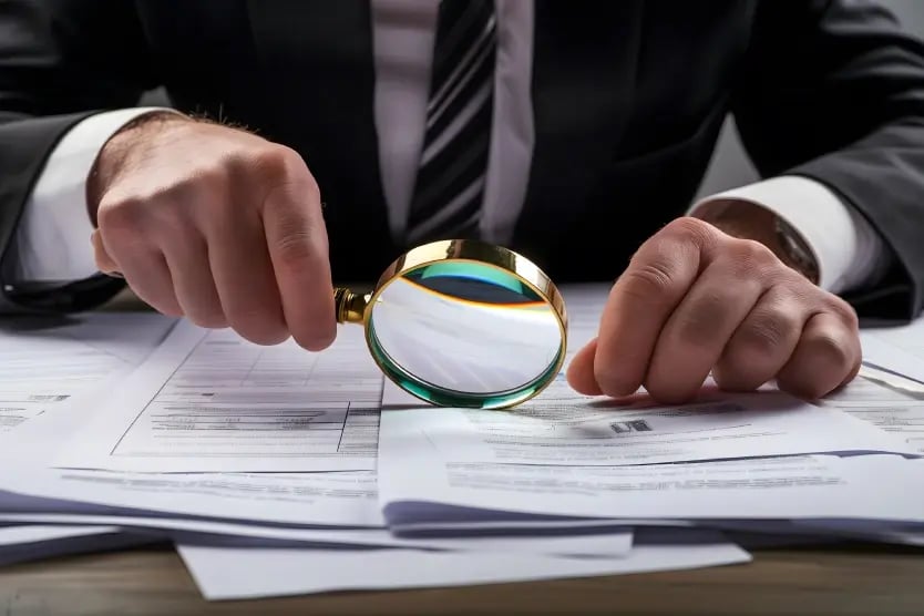 Professional in a suit carefully reviewing printed documents.
