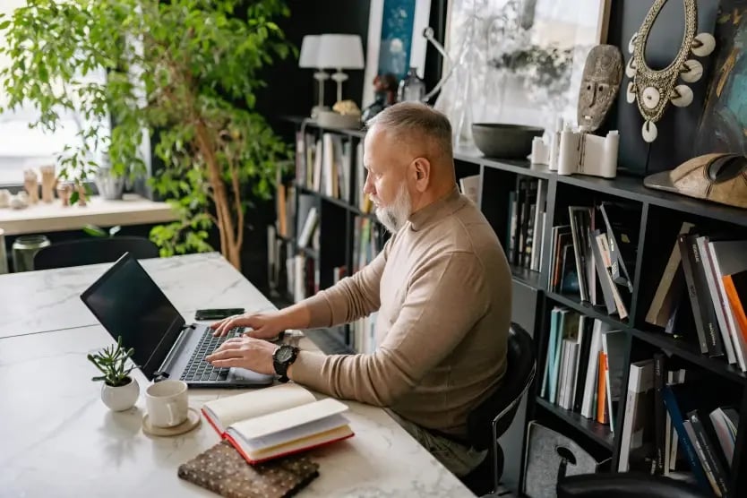 Person reading a laptop screen in their home library
