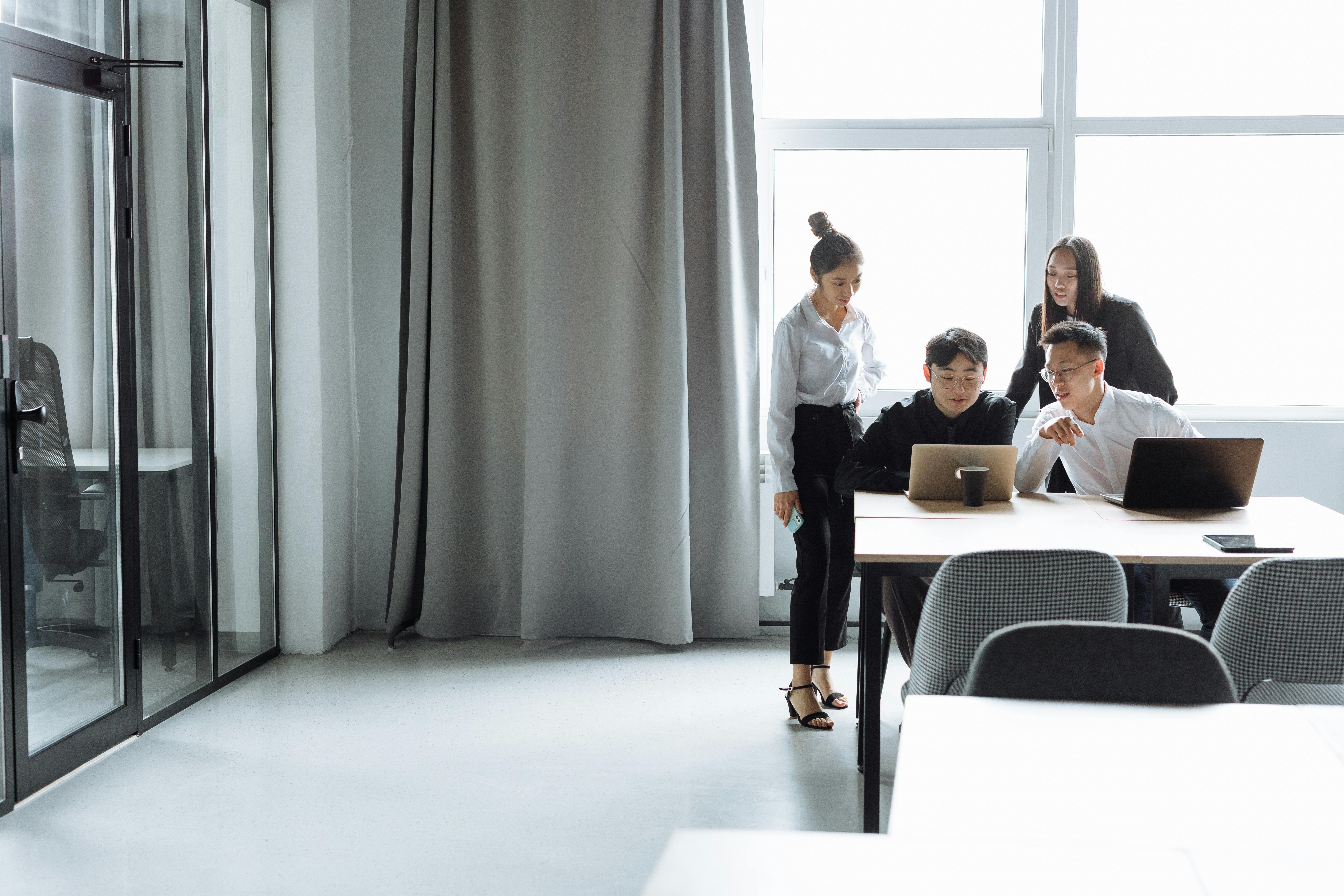 People collaborating around a laptop in an office setting.