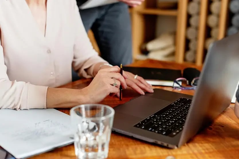 Person at laptop taking notes on a notepad
