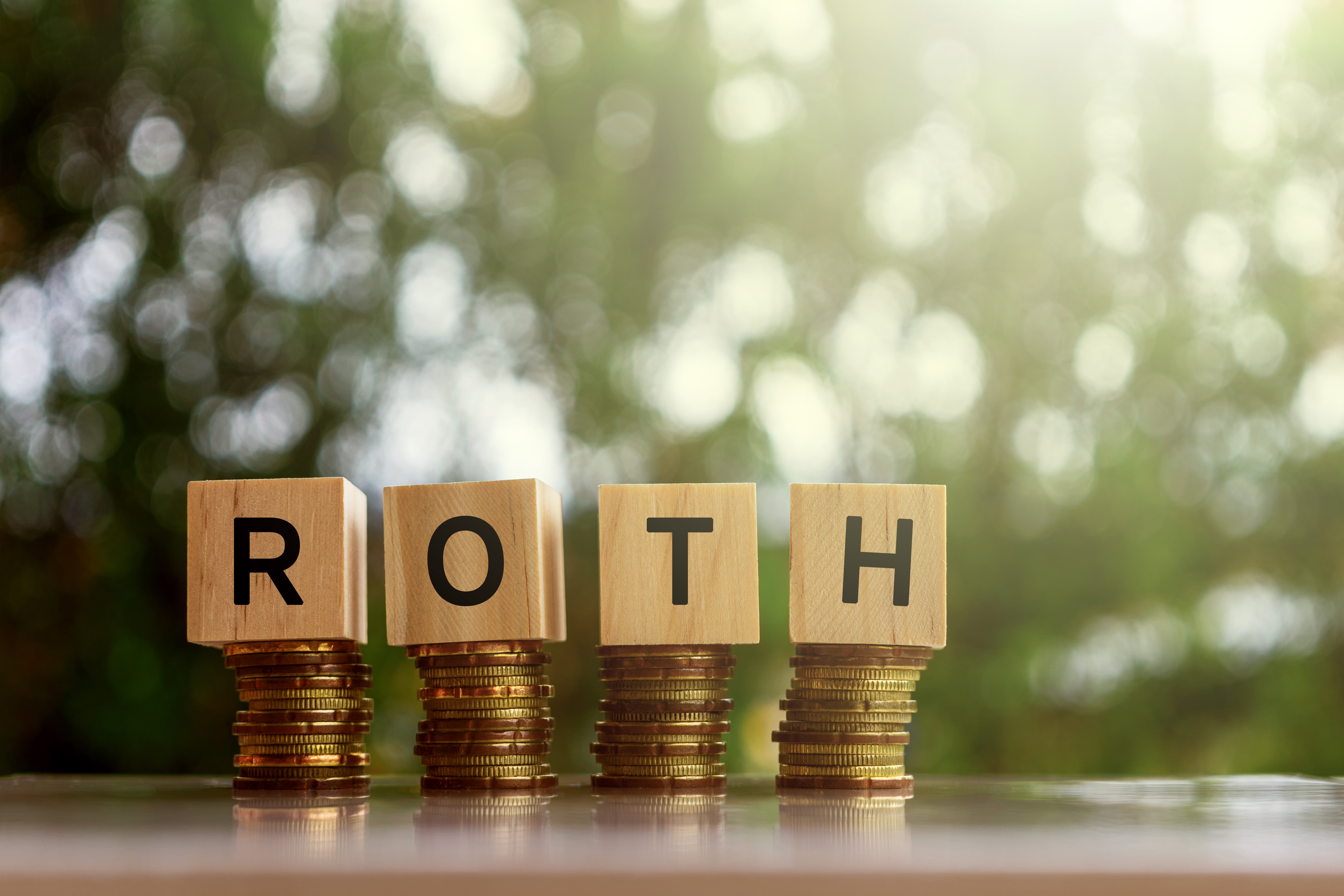 ROTH, spelled out using building blocks, sitting on top of coins.