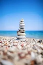 Stones stacked and balanced with a view of the beach and shore.